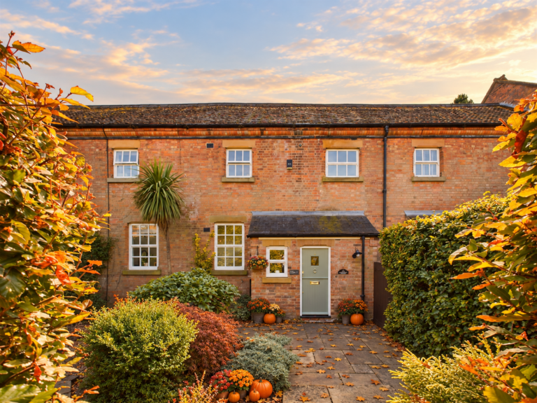Red-brick terraced home with autumn leaves and pumpkins by the front door