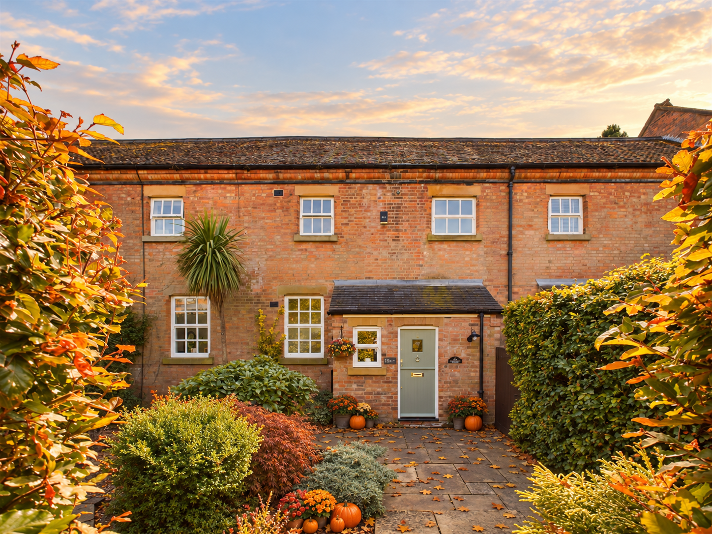 Red-brick terraced home with autumn leaves and pumpkins by the front door